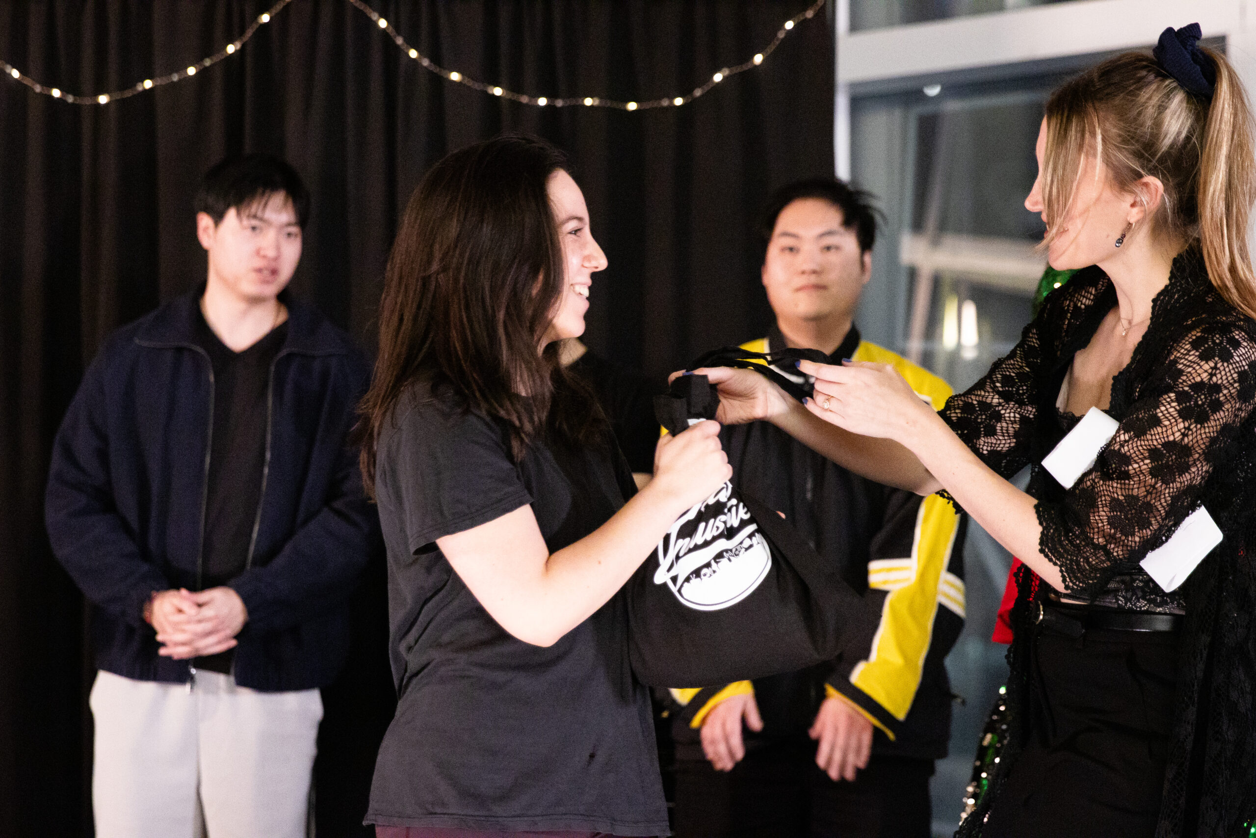 Woman taking a package from another woman while others watch.