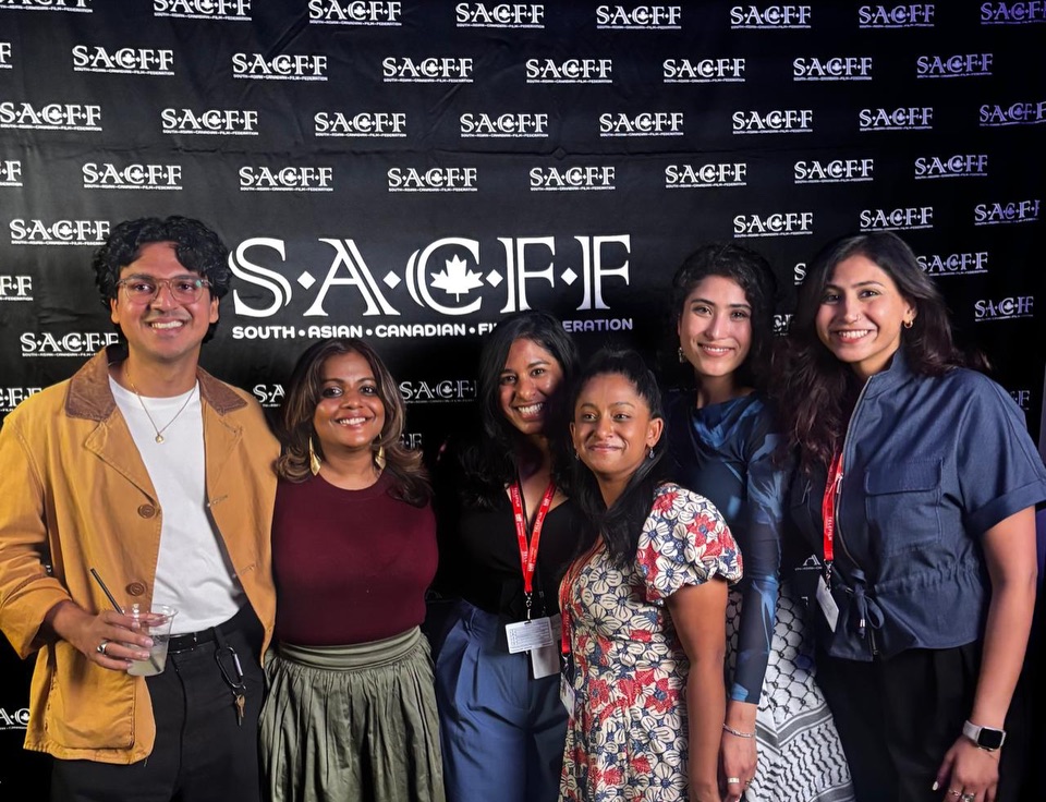 Fillmmakers at TIFF A group of participants standing in front of a South Asian Canadian Film Federation backdrop.