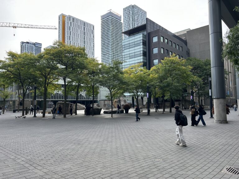 Students walk through Toronto Metropolitan University's campus with buildings visible in the background.