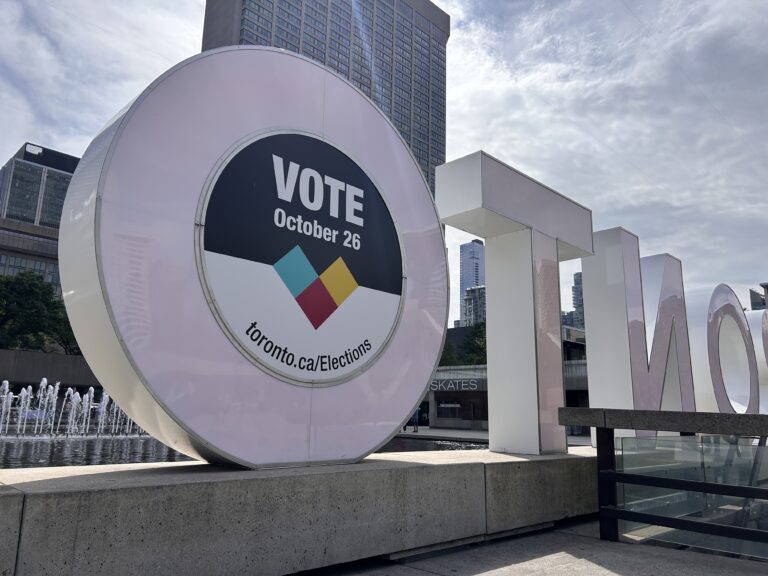 The back of the Toronto sign outside of Toronto City Hall. On the Back of one "O" is a sign saying "Vote October 26." and toronto.ca/Elections