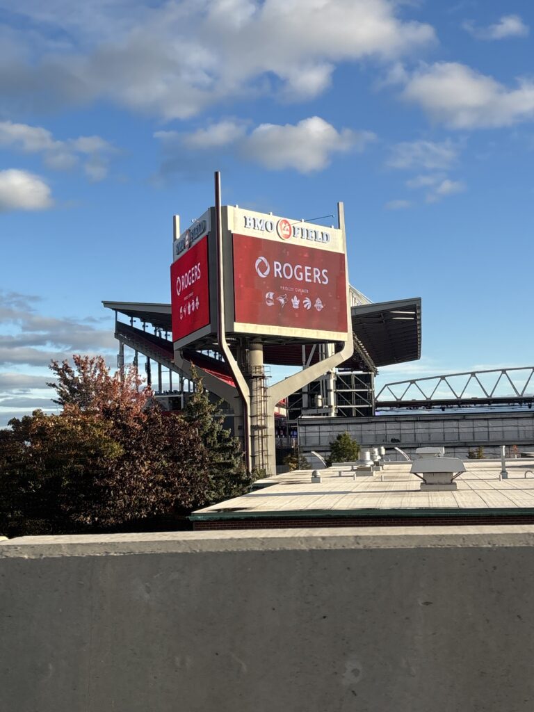 electronic board with red sign that reads "Rogers Proud Owner" with the logos of Toronto sports teams.