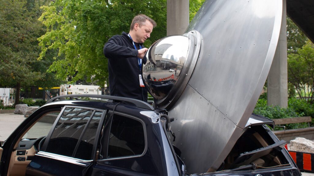 A man standing inside of a car that has been destroyed by a UFO.