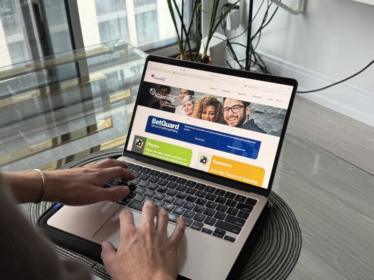 A person uses a laptop displaying the iGaming Ontario website and information about BetGuard, a tool for opting out of online gambling.