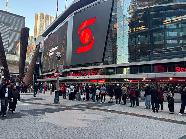 Groups of people line up outside of the Scotiabank Arena ahead of a basketball game