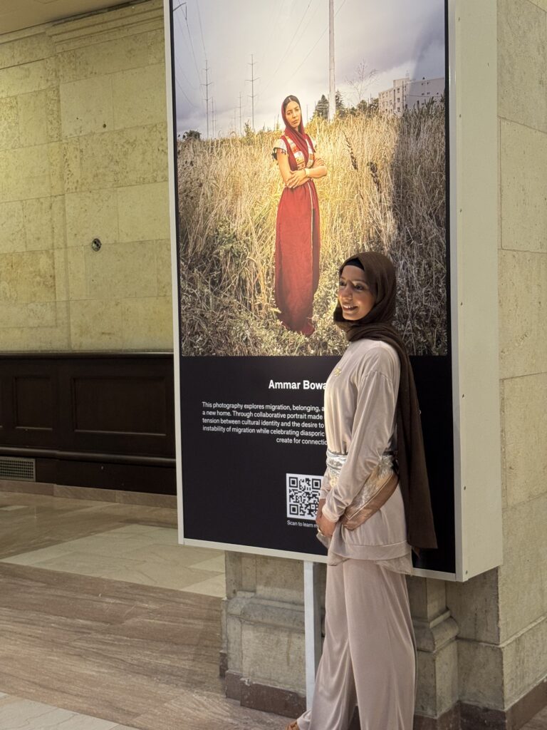 Huda Bowaihl stands beside her photograph, taken by Ammar (OTR/Mostafa Al-A’sar)