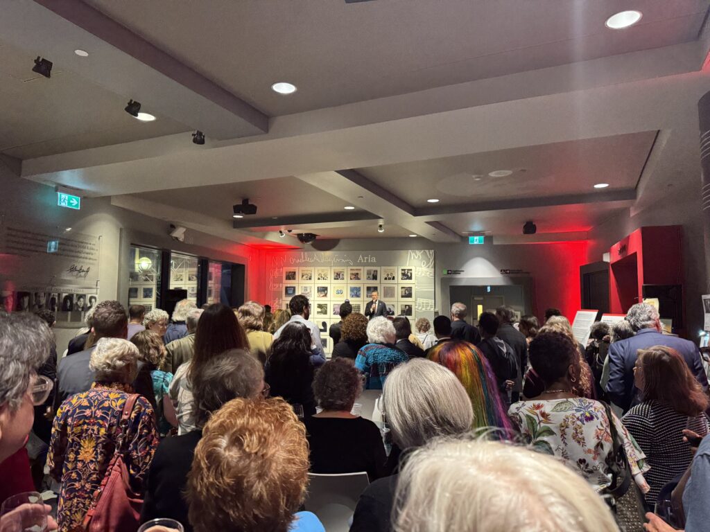 Large room with an audience watching a speaker during Joan Leishman Memorial Fund