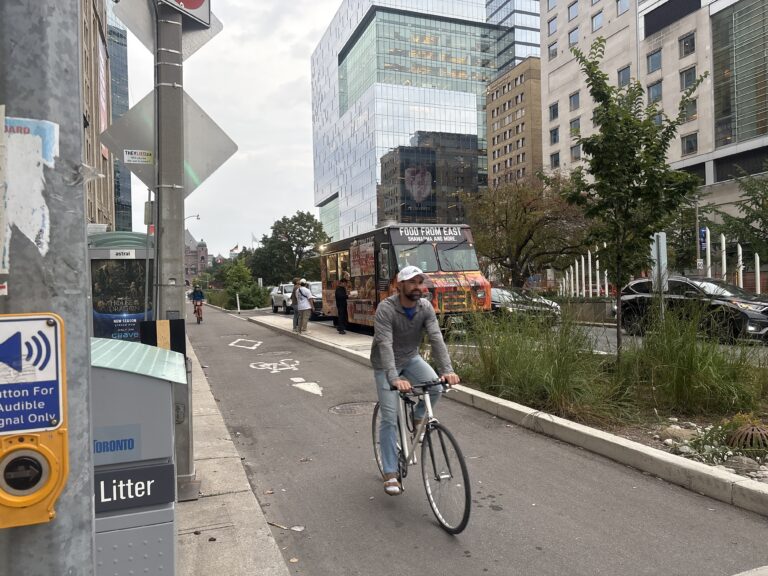 Bikers cycling in a bike lane on a busy street.