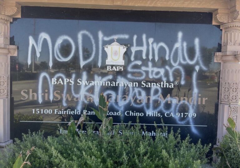 A black nameplate with white grafitti on it.