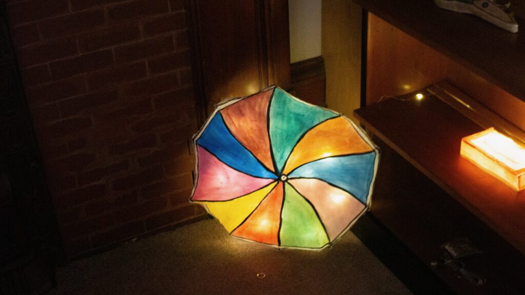 A paper crafted top half of an umbrella with rainbow pattering.