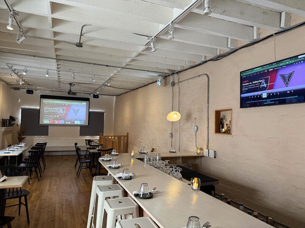 A photo of an empty bar space with two TVs on the walls.