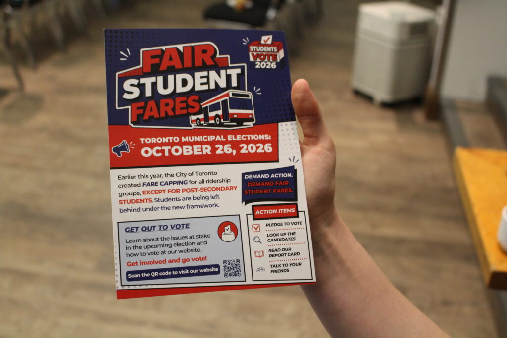 RAAKMAN-HERRICK-IMAGE-1 A hand holding a red, white, and blue holder advertising TTCRiders and TMAPS' Fair Student Fares event.