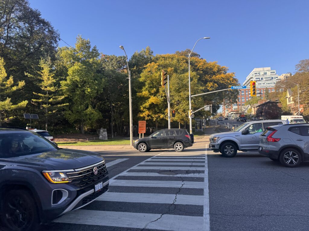 The outskirts of High Park with cars turning on the road near the Parkside entrance of the park