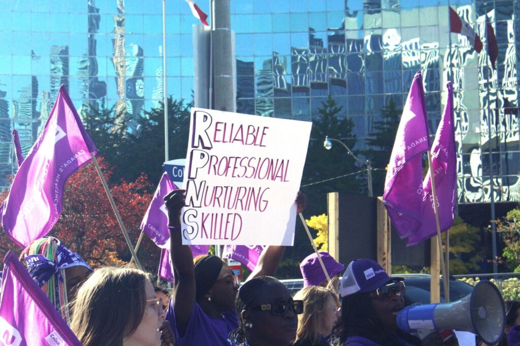 People in a group with flags, signs and microphones
